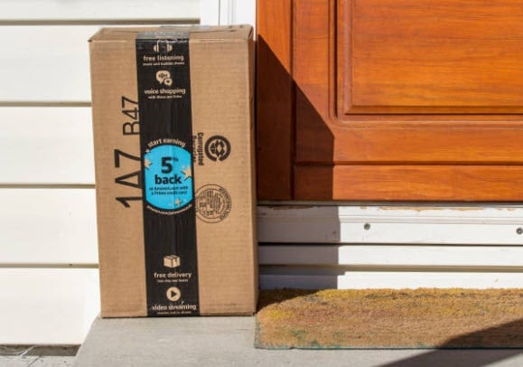 Cardboard box with blue circle label and number 5 sitting on doormat in front of wooden door